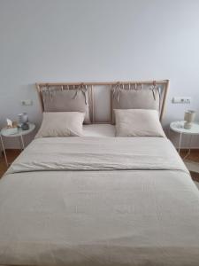 a bed with white sheets and pillows and two tables at Beautiful luxury apartment with sea view Mojacar Playa in Mojácar