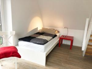 ein kleines Schlafzimmer mit einem Bett und einem roten Tisch in der Unterkunft Schlei 48 in Borgwedel
