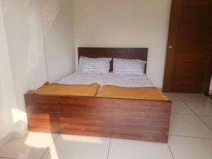 a bed in a room with a wooden bed frame at Be My Guest Homestay WHISPERING WIND in Kolhapur