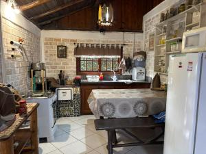 a kitchen with a refrigerator and a table in it at Casa Mágica in Praia do Rosa