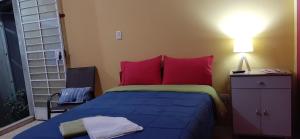 Schlafzimmer mit einem Bett mit roten und grünen Kissen in der Unterkunft Departamento 6p Tierra del Sol Eterno - Ica centro in Ica