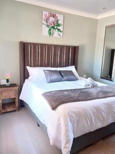 a bedroom with a large bed with a wooden headboard at Precious Estates Emerald in Zeerust