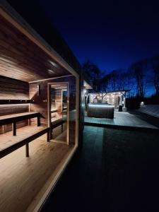 a wooden house with a bench on a deck at night at Vila Casa din gradina in Voivodeni