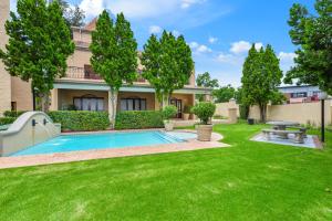 a yard with a swimming pool in front of a house at Modern 2 Bedroom apartment with club house pool in Sandton