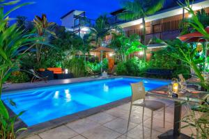 - une piscine avec une table et des chaises la nuit dans l'établissement Hotel Ker Alberte, à Cayenne