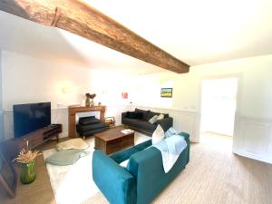 a living room with a blue couch and a tv at La Ferme familiale de Percy - 9 pers in Percy-en-Auge