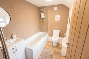 a bathroom with a tub and a toilet and a sink at No 4 John Street in Bethesda +18 photos