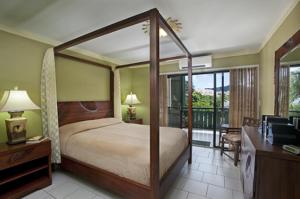 a bedroom with a canopy bed and a balcony at Colony Cove Beach Resort in Christiansted