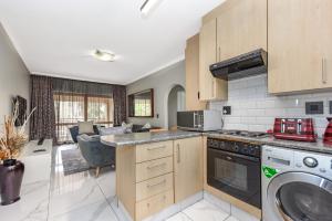 a kitchen with a stove top oven next to a living room at Modern 2 Bedroom apartment with club house pool in Sandton