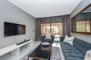 a living room with a couch and a tv at Modern 2 Bedroom apartment with club house pool in Sandton