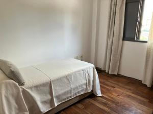Un dormitorio con una cama con una manta blanca encima. en Dpto tranquilo pleno Centro-Sur con Cochera, en Santa Fe