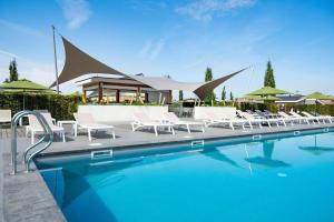 a swimming pool with white chairs and a building at Ravenbosch - Sauna in Valkenburg