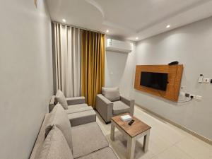 a living room with a couch and a tv at نجمة راحتي للشقق المخدومة العزيزية in Riyadh