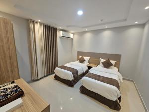 a hotel room with two beds and a table at نجمة راحتي للشقق المخدومة العزيزية in Riyadh