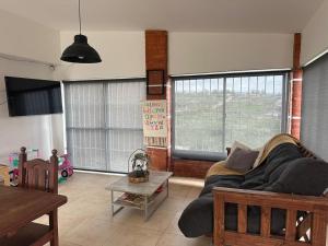 a living room with a couch and two large windows at Casa en Tanti con pileta in Tanti