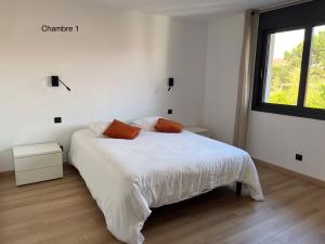 a white bedroom with a bed with two orange pillows at Sole e Mare in Mimizan-Plage