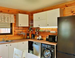 a kitchen with white cabinets and a black refrigerator at The Village Cottage in Natsovtsi