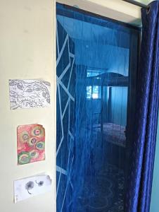 a room with a blue curtain and a window at Beach Clan Dorms in Alleppey