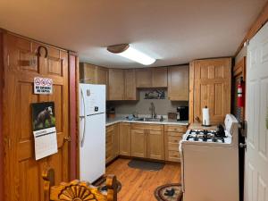 a kitchen with wooden cabinets and a white refrigerator at Gonzales Cozy Little Bear Cabin in Ruidoso