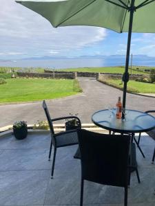 a table and chairs with an umbrella on a patio at Ocean Spray Self Catering apartment in Kilcar