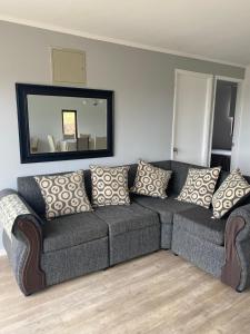 a couch with pillows in a living room with a mirror at Cabaña Viaducto Vista al Mar, Curanipe in Pelluhue