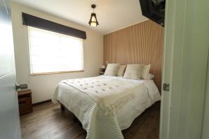 a bedroom with a white bed with a window at Departamentos Nómades del Lago in Puerto Varas