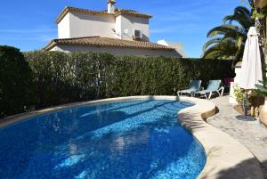 a swimming pool with two chairs and a house at Anacasa Picasso Oliva Nova CH1400 in Oliva