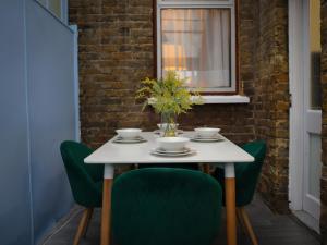 a white table with green chairs and a vase of flowers at London 4 Bed Contractor Base with Pool Table in Edmonton