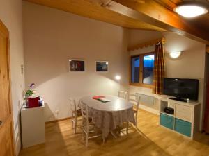 a dining room with a table and chairs and a tv at Apt Sakura - Le Grand Tetras in Samoëns
