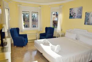 ein Schlafzimmer mit einem großen weißen Bett und zwei blauen Stühlen in der Unterkunft Anacasa Villa Renoir Oliva Nova CH1015 in Oliva + 56 Fotos