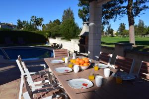 ein Holztisch mit Obst darauf neben einem Pool in der Unterkunft Anacasa Villa Murillo Oliva Nova MET CH1900 in Oliva