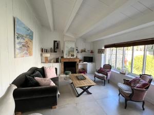 ein Wohnzimmer mit Sofa, Stühlen und einem Tisch in der Unterkunft Maison LA BEURELIÈRE proche Plage in Sainte-Marie-de-Ré