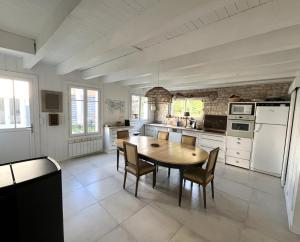 eine große Küche mit Holztisch und Stühlen in der Unterkunft Maison LA BEURELIÈRE proche Plage in Sainte-Marie-de-Ré