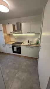 a kitchen with white cabinets and a sink and a stove at Ruhige Wohnung mit Garten in Schönefeld