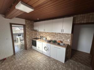 a kitchen with white cabinets and a washer at Zauberblick in Lindenfels +11 photos