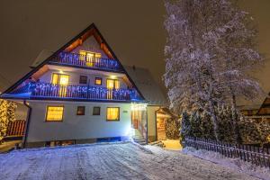 a house with blue lights on it in the snow at Apartamenty i Pokoje Teklarz & SPA in Murzasichle