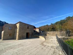 a stone building with a stone wall and a fence at Quinta Pazo Corisca in Salceda