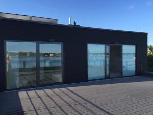 a black building with glass windows and a body of water at Fjordhaus Schleiwind in Fahrdorf