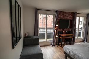 a bedroom with a bed and a desk and a window at Hotel De Quebec in Rouen