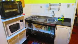 a small kitchen with a sink and a microwave at Apt térreo Gonçalves Chaves prox Bento in Pelotas +8 photos
