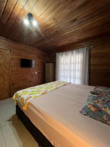 Pântano GrandeにあるQuarto em casa familiarの木製の天井と大きなベッドのある寝室