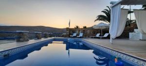 a swimming pool with chairs and umbrellas next to a building at Cycladic House KRIOS with a Pool and 2min from the beach in Kithnos