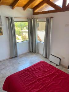 a bedroom with a red bed and a large window at Cabaña Rubí, Complejo El Colibrí in Villa del Dique