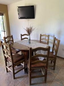 a dining room table and chairs with a tv on the wall at Cabaña Rubí, Complejo El Colibrí in Villa del Dique