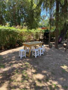 a picnic table and four white chairs in a park at Cabaña Rubí, Complejo El Colibrí in Villa del Dique