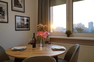 a wooden table with a bottle of wine and flowers on it at Simply Apartament - Symfonia z parkingiem in Toruń
