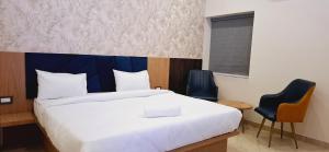 a bedroom with a large bed and two chairs at BlueNeck Ayodhya-Near ShriRam Mandir in Ayodhya