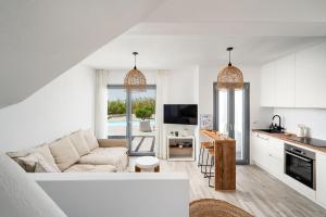 ein weißes Wohnzimmer mit einem Sofa und einer Küche in der Unterkunft Villa isola plaka Naxos in Plaka