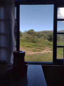 an open window with a view of a field at Achô na Roça STL in São Thomé das Letras