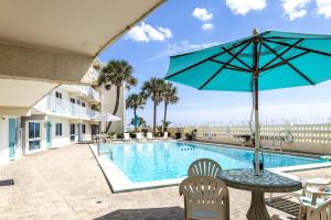 a table with an umbrella next to a swimming pool at Aqua Villa #105 Beachside 2 bedroom condo in Fort Walton Beach